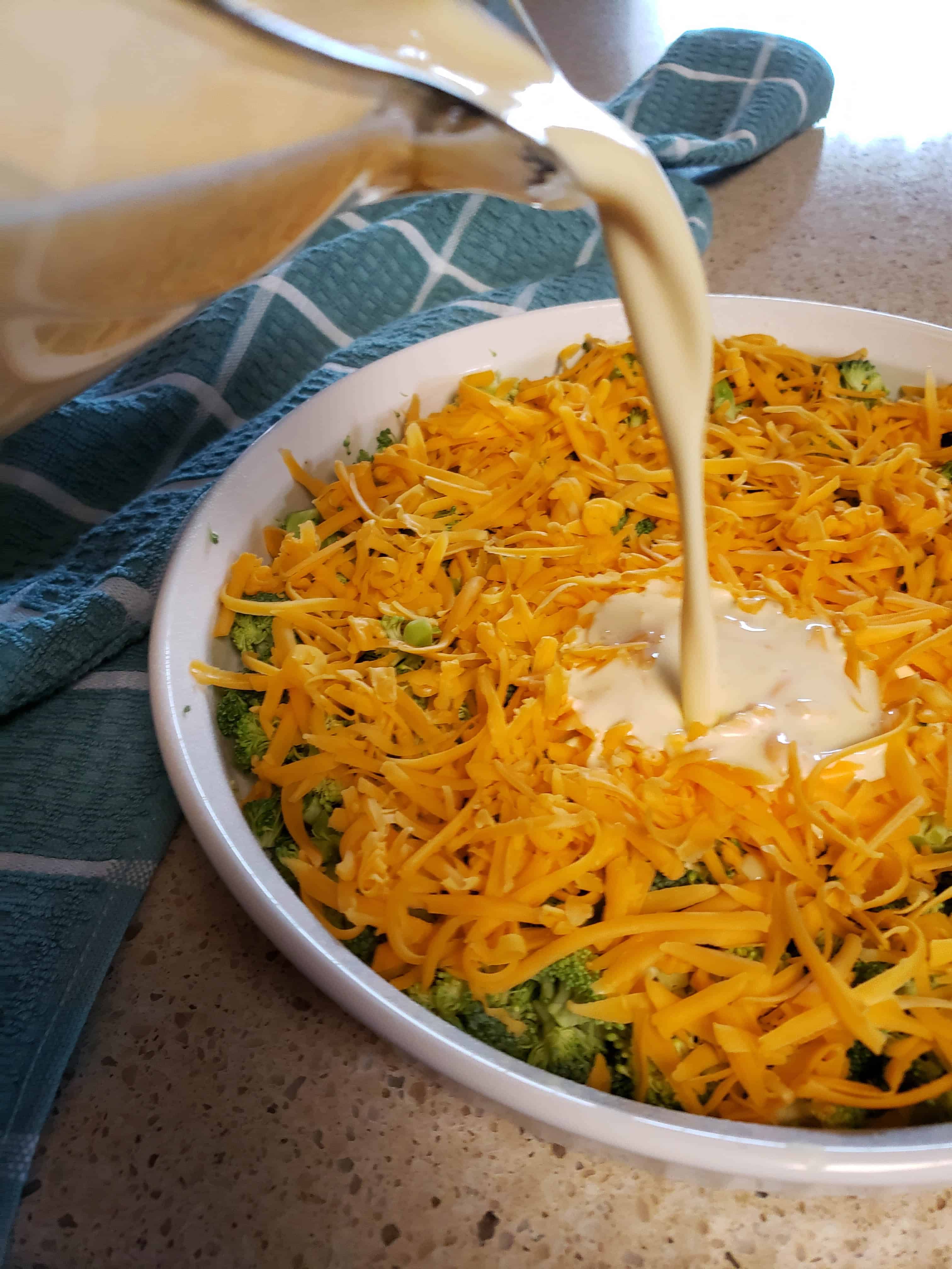 Pouring custard over the broccoli and cheddar for the keto quiche