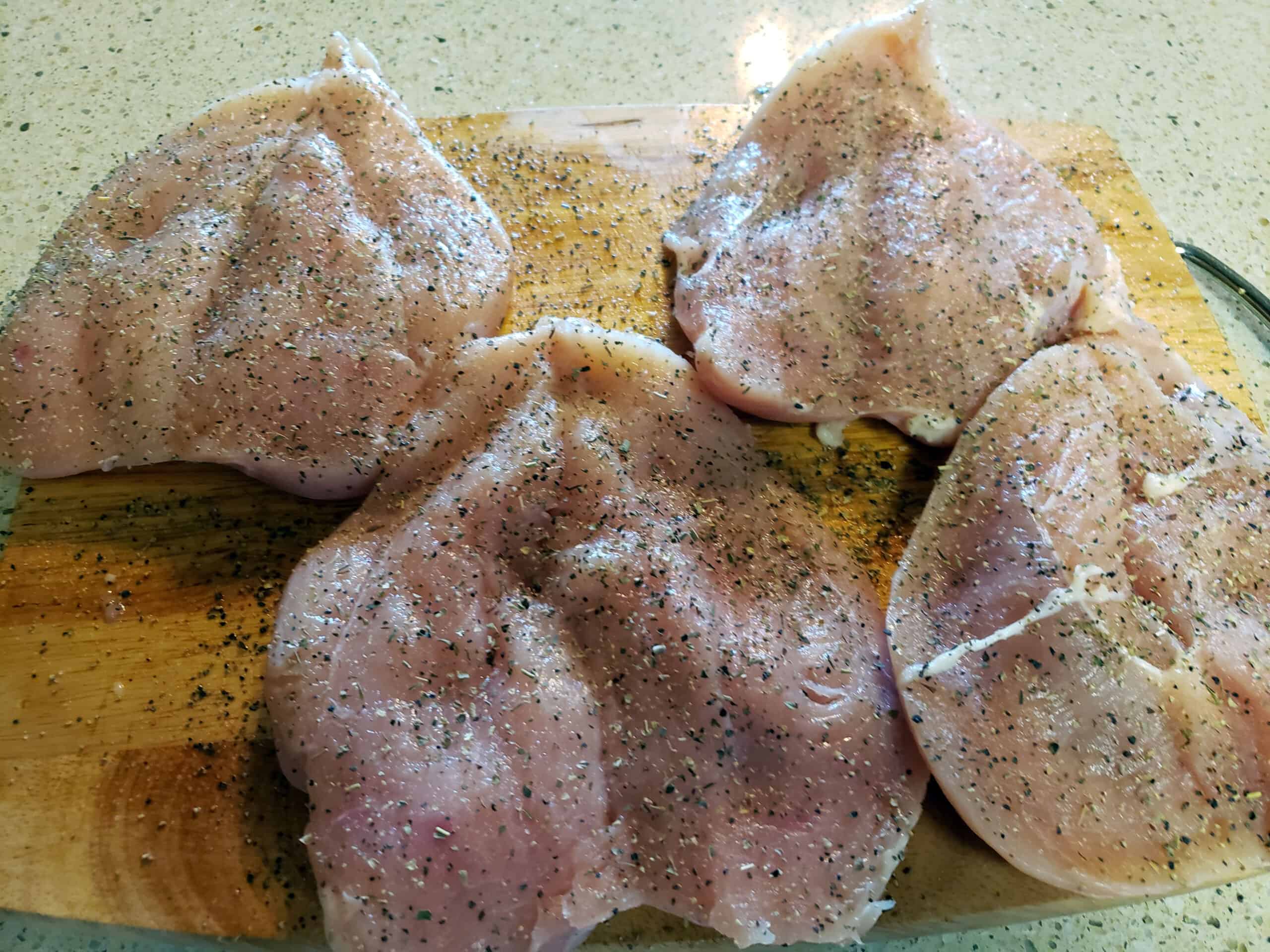 seasoned, butterflied chicken breasts on cutting board